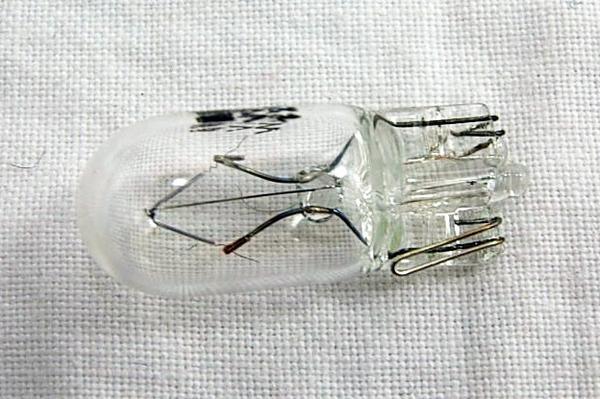 Clear glass motorcycle bulb with dual filaments and metal base for ATV, scooter, or dirt bike lighting