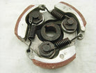 Close-up of a metal centrifugal clutch with springs and friction pads on a white fabric background