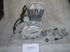 Silver Loncin 150cc ATV engine with wiring and mounting parts on grey fabric background
