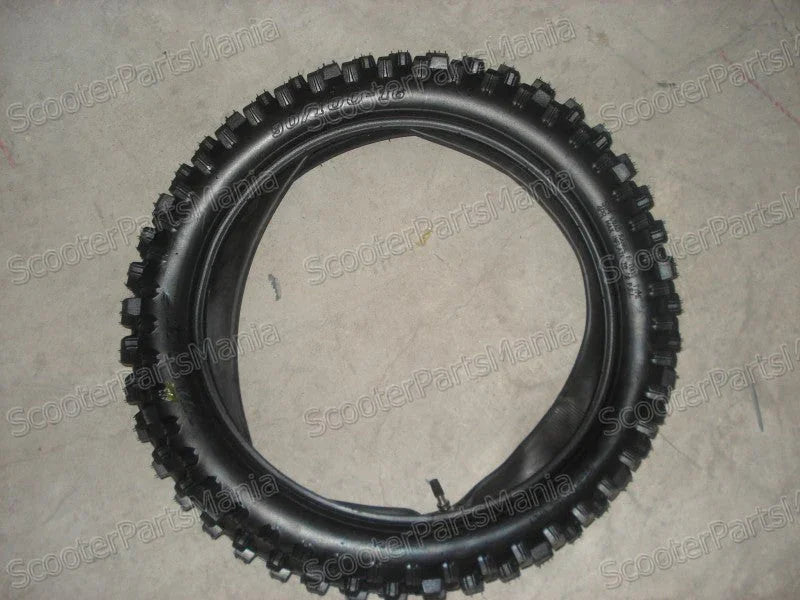 Black knobby off-road dirt bike tire and inner tube on a concrete floor