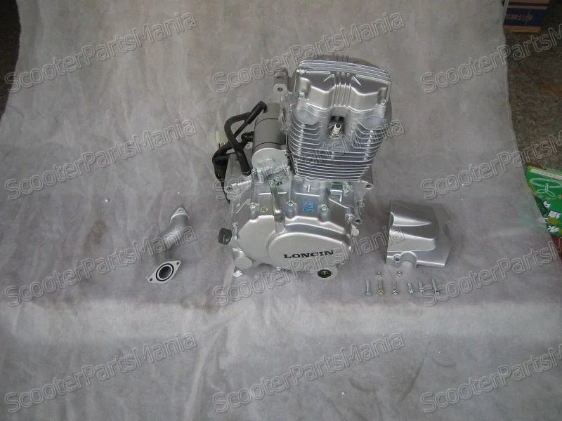 Silver Loncin small motorcycle engine with mounting parts and screws on gray surface