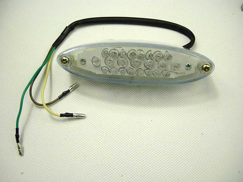 Oval LED motorcycle tail light with multiple clear lenses and three colored wires on white background