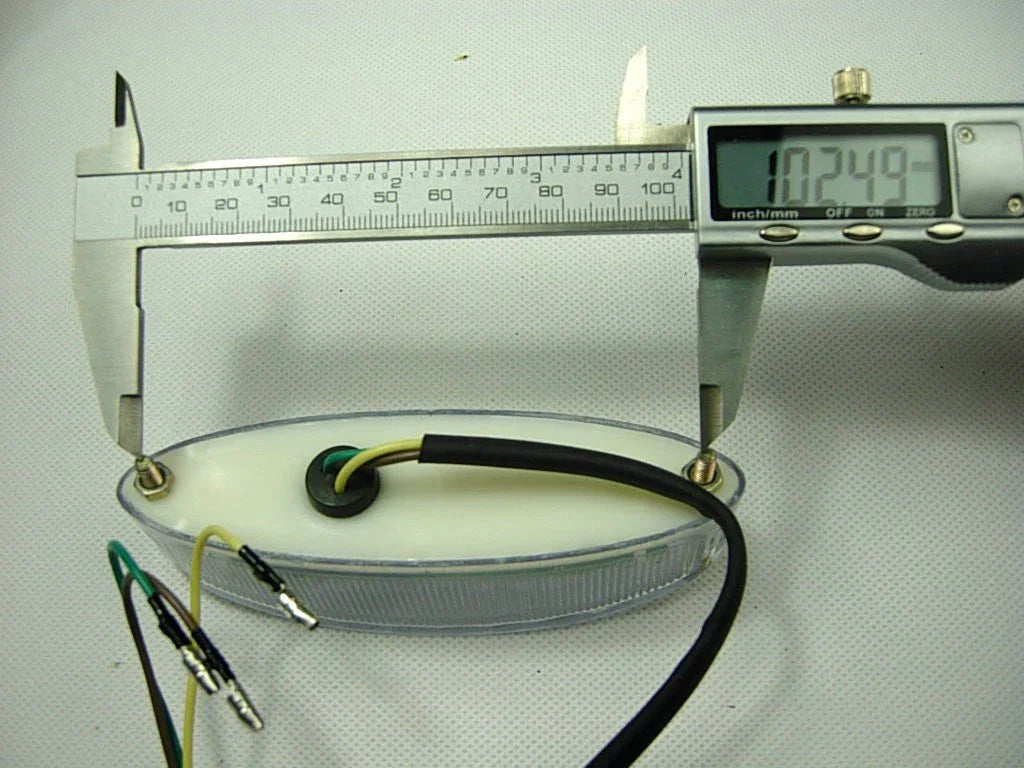 Digital caliper measuring 102.49 mm length of oval LED trailer side marker light with wires