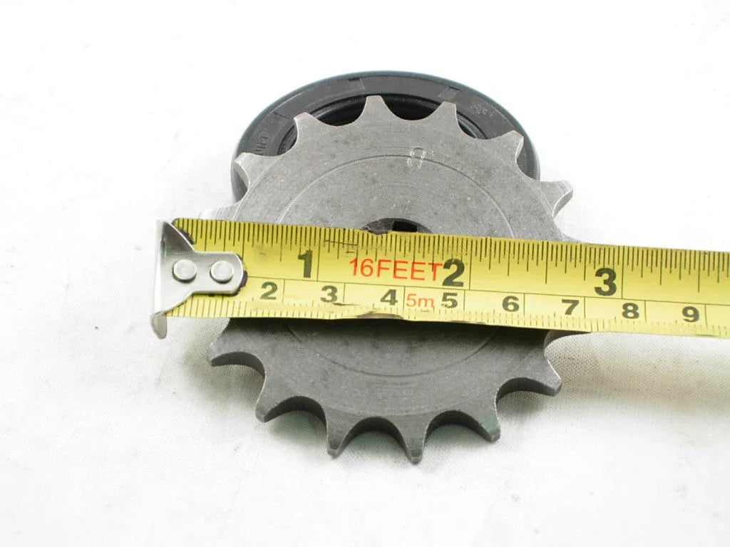 Close-up of a metal sprocket gear with a yellow measuring tape across it showing about 3 inches