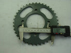 Green metal sprocket gear with digital caliper measuring 90.13 mm diameter on gray background