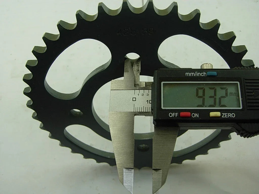 Digital caliper measuring 9.32 mm thickness of a black metal sprocket gear with teeth