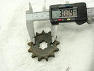 Digital caliper measuring 30.09 mm on a rusty metal sprocket gear with ten teeth on a white surface