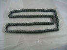 metal roller chain laid flat on light gray surface for industrial machinery