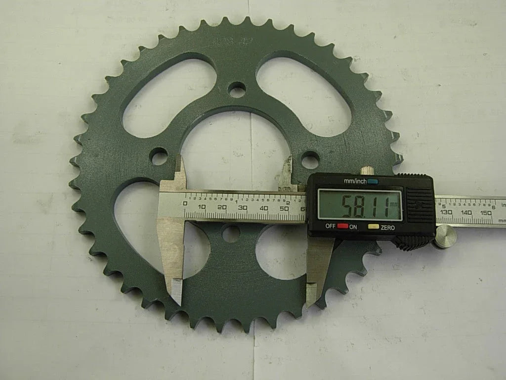 digital caliper measuring 58.11 mm on a green metal sprocket gear with teeth