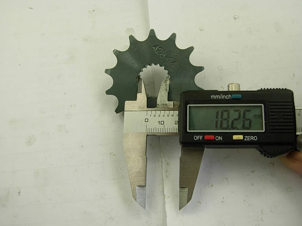 Digital caliper measuring diameter of black metal sprocket gear marked 428-14, showing 18.26 mm