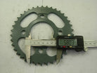 Digital caliper measuring 58.03 mm diameter of green metal sprocket on white surface