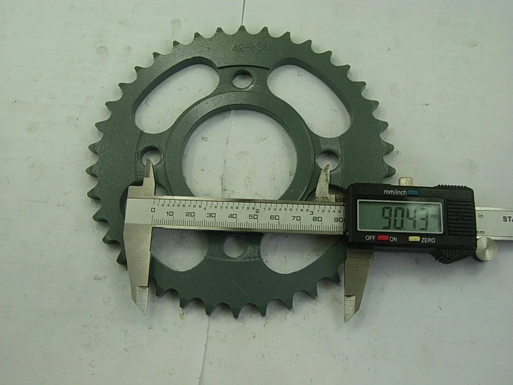 Digital caliper measuring 90.43mm on green metal sprocket gear with teeth on white surface