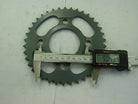 Digital caliper measuring 90.43mm on green metal sprocket gear with teeth on white surface
