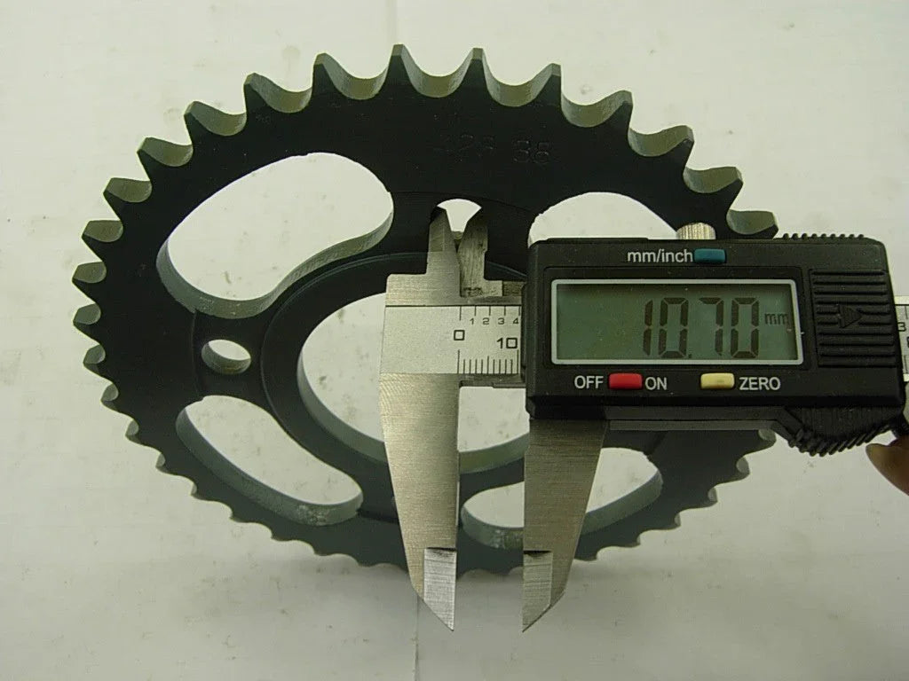 Digital caliper measuring 10.70 mm thickness of black metal sprocket gear