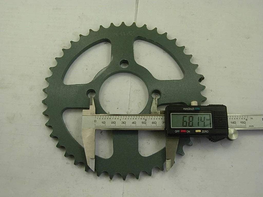 Digital caliper measuring 68.14 mm on green metal bike sprocket with 44 teeth