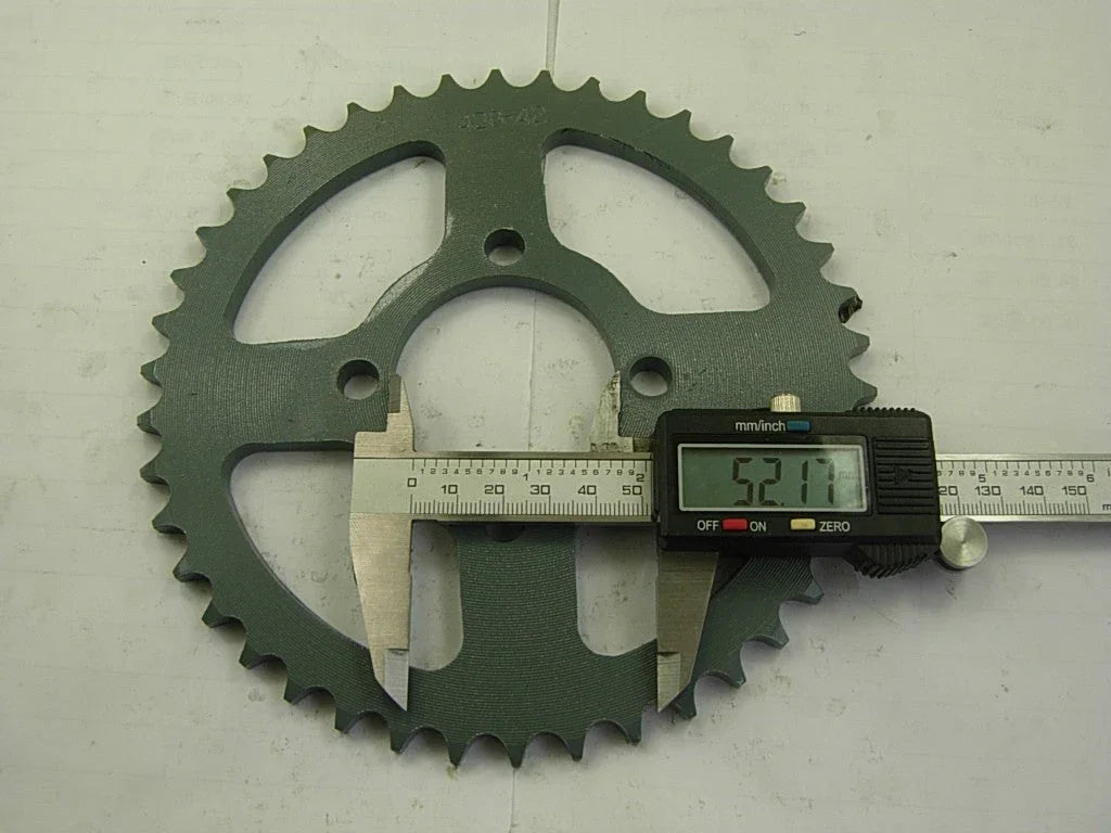 Dark green metal sprocket measured with digital caliper showing 52.17 mm on white surface