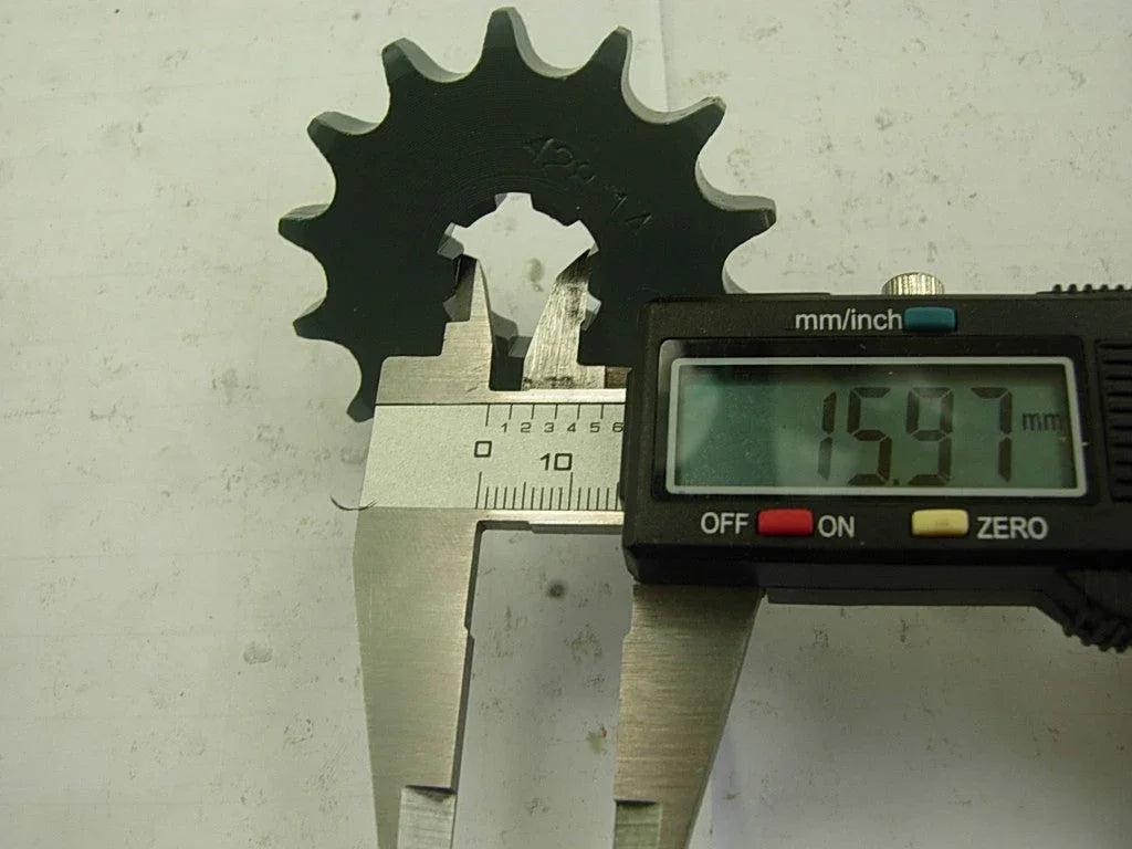 Digital caliper measuring black sprocket gear thickness showing 15.97 mm on display