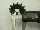 Digital caliper measuring 20.15 mm diameter of metal cogwheel gear on white surface