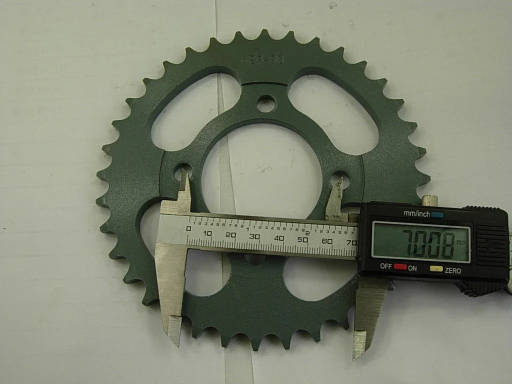 Green metal bicycle sprocket gear measured with digital caliper showing 70.08 mm diameter