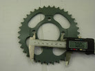 Green metal bicycle sprocket gear measured with digital caliper showing 70.08 mm diameter