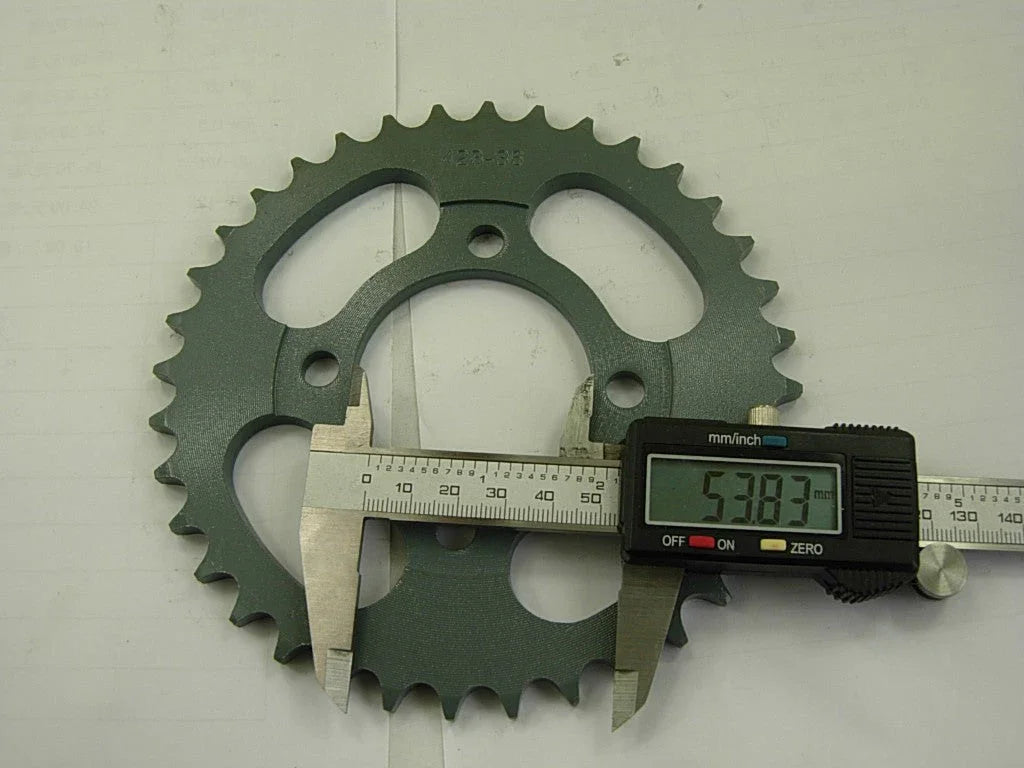 Green metal bicycle sprocket gear with digital caliper measuring 53.83 mm diameter on a white background