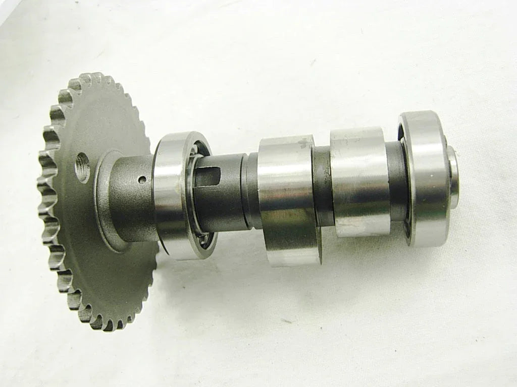 Metal camshaft with gear and bearings on a white background