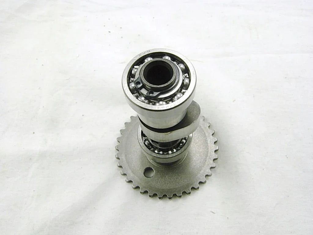 metal camshaft with visible ball bearings and gear teeth on white background