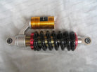 Black coil spring motorcycle shock absorber with gold reservoir and silver mounting eyes