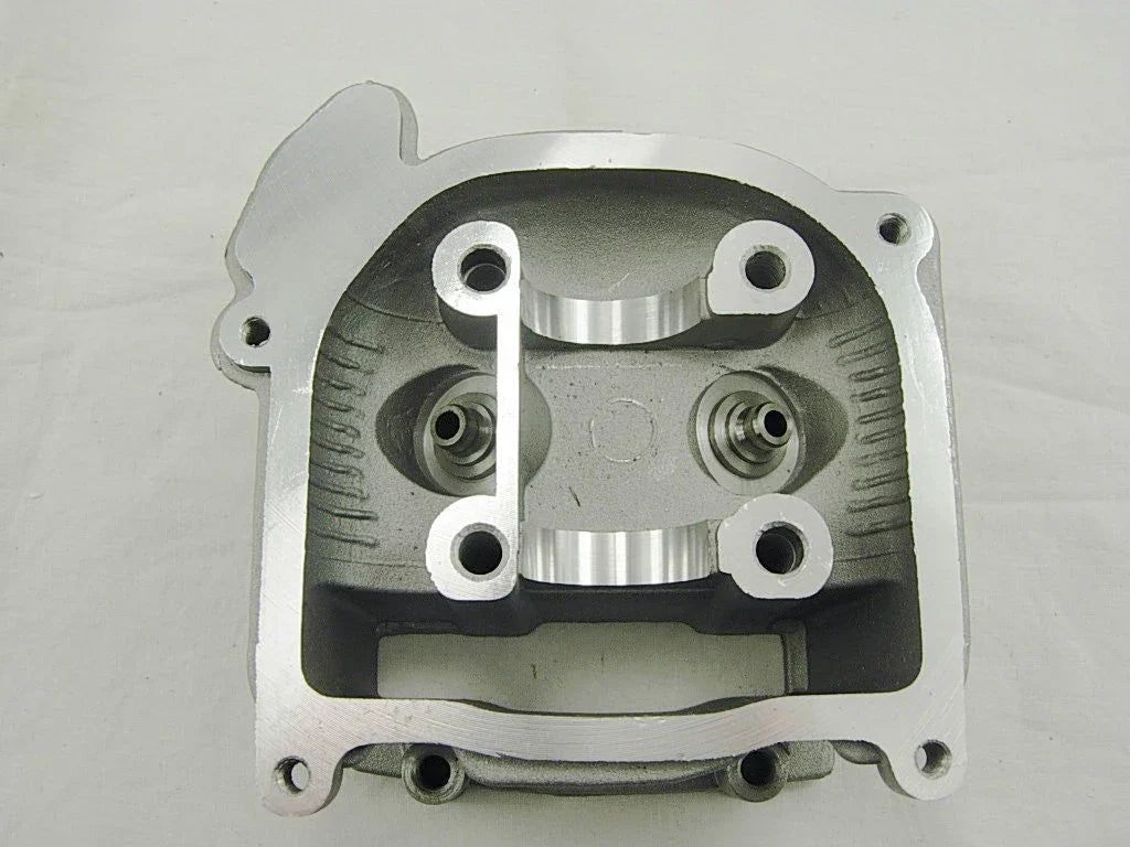 Silver metallic cylinder head engine part with valve seats and mounting holes on white background