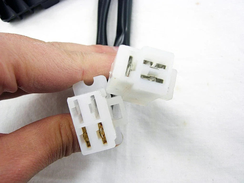 Hand holding two white 4-pin electrical wire connectors against a white background