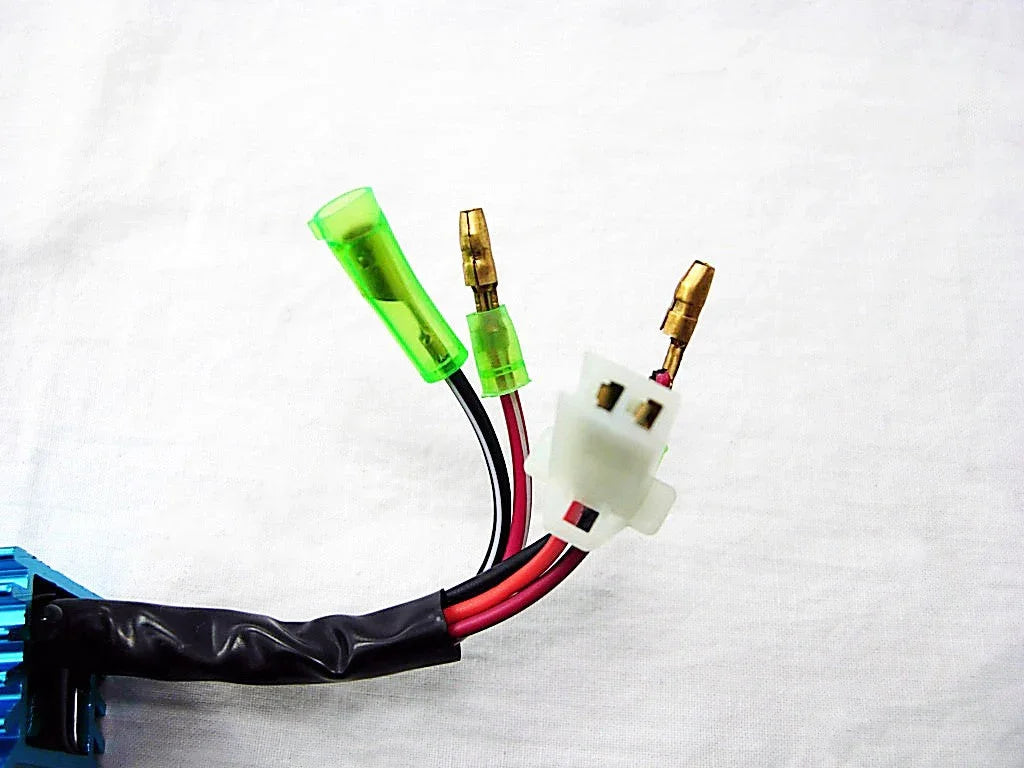 Close-up of electrical wires with green insulated connectors and a white plastic connector on a white background