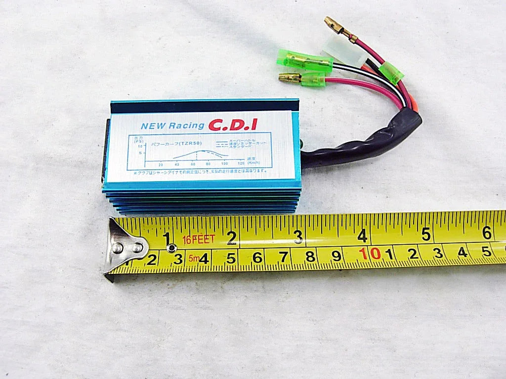 Blue NEW Racing C.D.I motorcycle ignition module with wiring and measuring tape on white surface