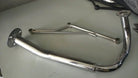 Shiny chrome exhaust pipe for motorcycle or ATV, featuring curved design and mounting flanges