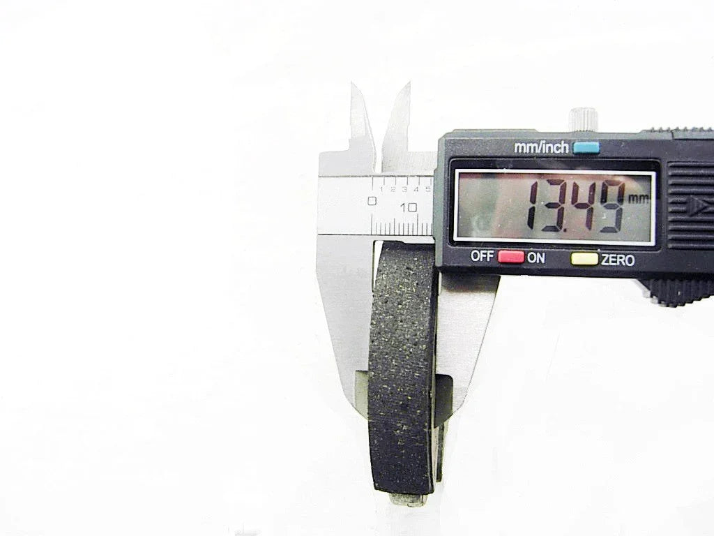 Digital caliper measuring thickness of a black rubber washer showing 13.49 mm