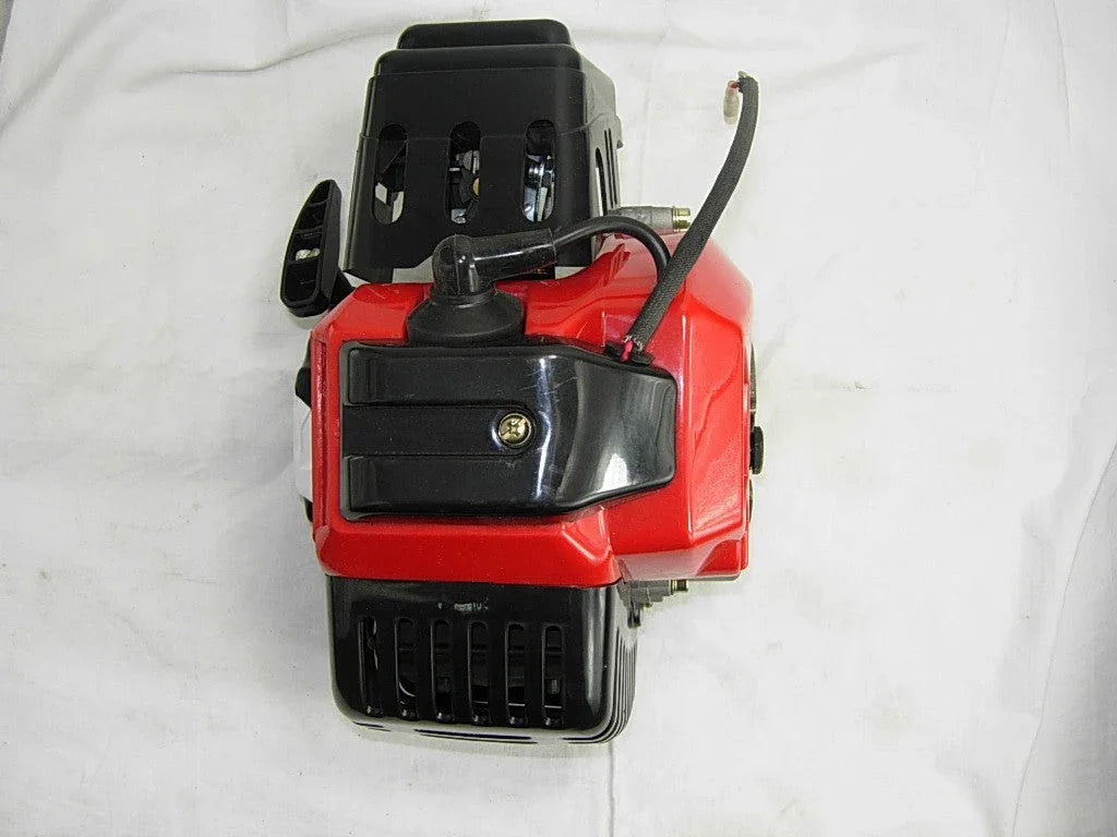 Compact red and black gasoline engine motor with cooling vents and attached spark plug wire on white background