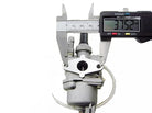 Carburetor being measured with digital caliper showing 37.52 mm on white background