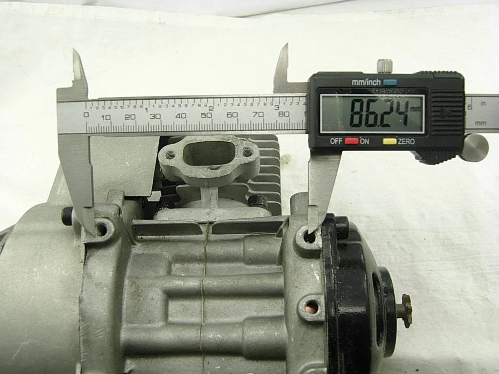 Digital caliper measuring 86.24 mm on a metal engine cylinder component in workshop